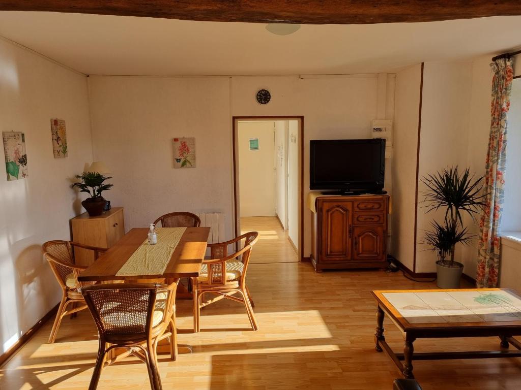 ein Wohnzimmer mit einem Tisch und einem TV in der Unterkunft Pied à Terre Chaumont in Chaumont