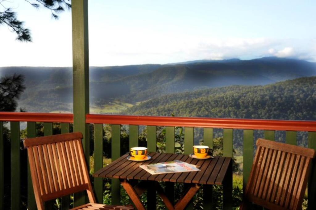 una mesa con 2 sillas y 2 tazas en el balcón en Clouds Chalet, en Beechmont