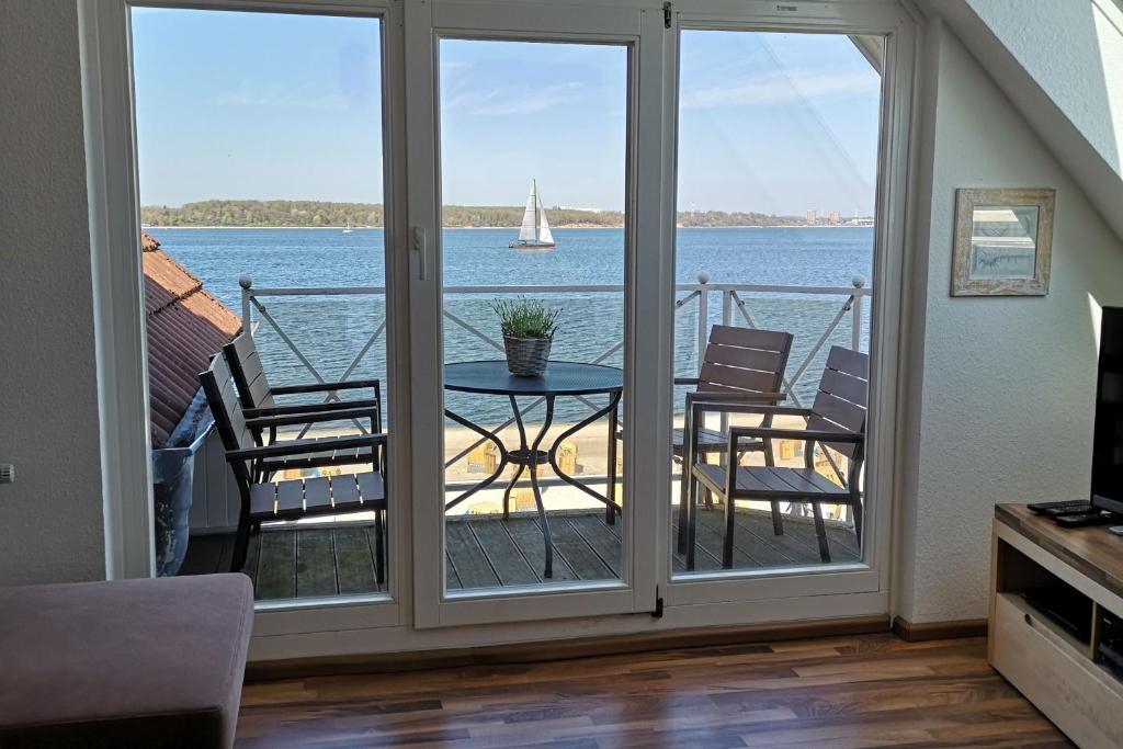 uma varanda com uma mesa e cadeiras com vista para a água em Strandhotel 37 em Laboe