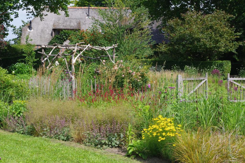un jardín con una variedad de plantas y flores en Farmhouse De Hoeve B&B apartment, en Tonden