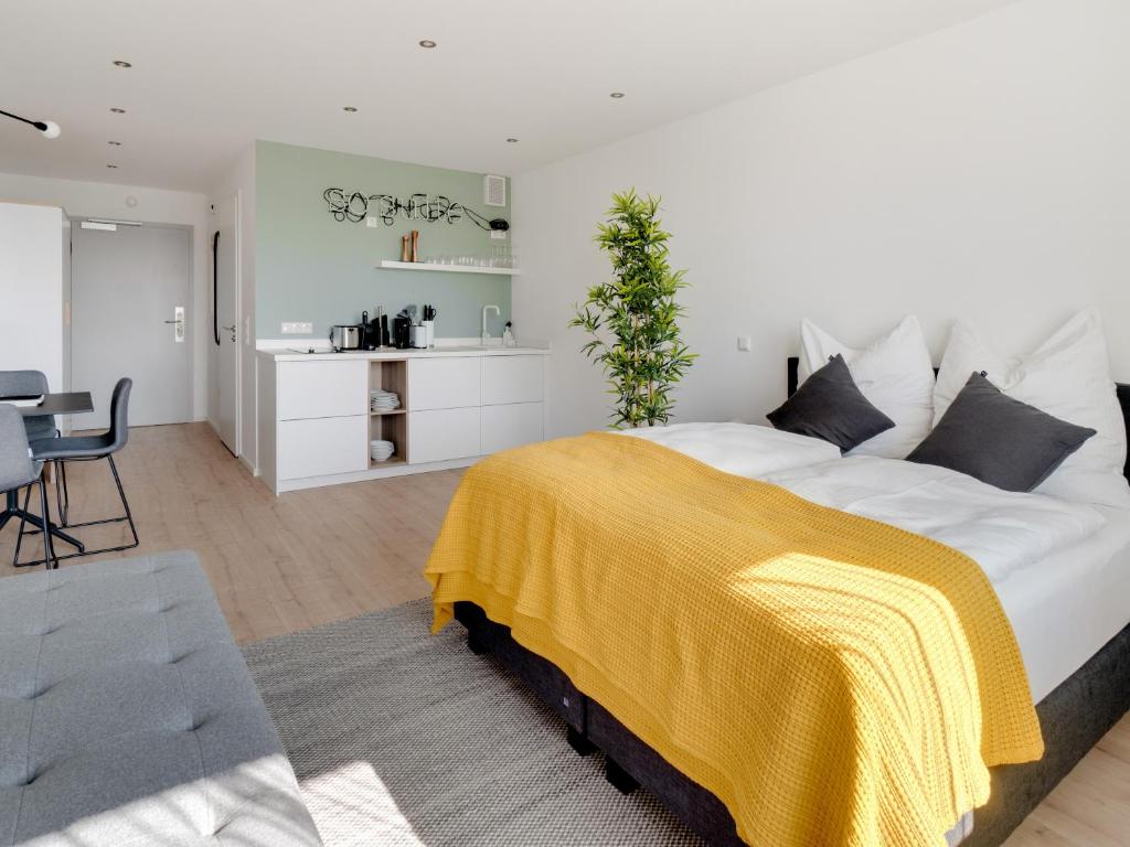 1 dormitorio con 1 cama grande con manta amarilla en limehome Darmstadt Wilhelminenstraße - Digital Access, en Darmstadt