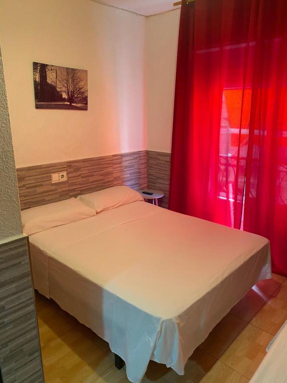 a bedroom with a bed with red curtains and a window at PENSIÓN ROSA in Benidorm