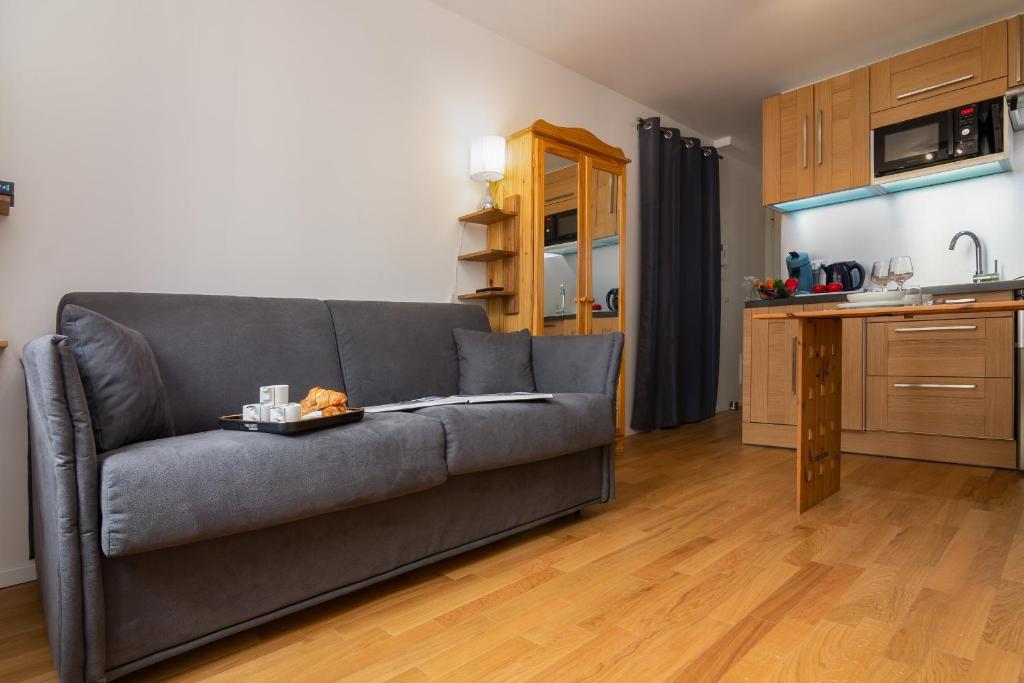 a living room with a gray couch and a kitchen at Appartement Paccard 305 - Happy Rentals in Chamonix