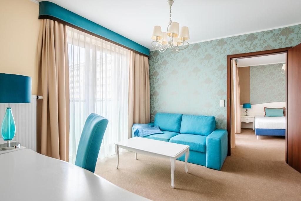 a room with a blue couch and a bed at Hotel Opole Centrum in Opole