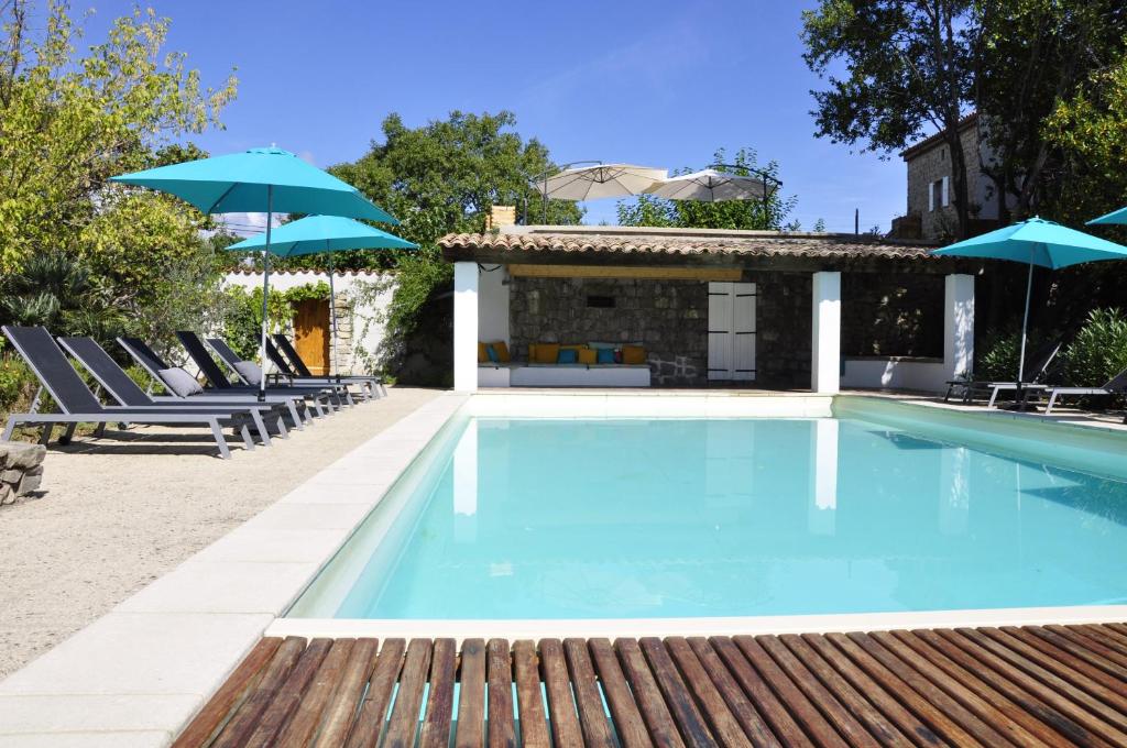 a swimming pool with lounge chairs and umbrellas at Un je ne sais quoi de Paradis in Les Vans