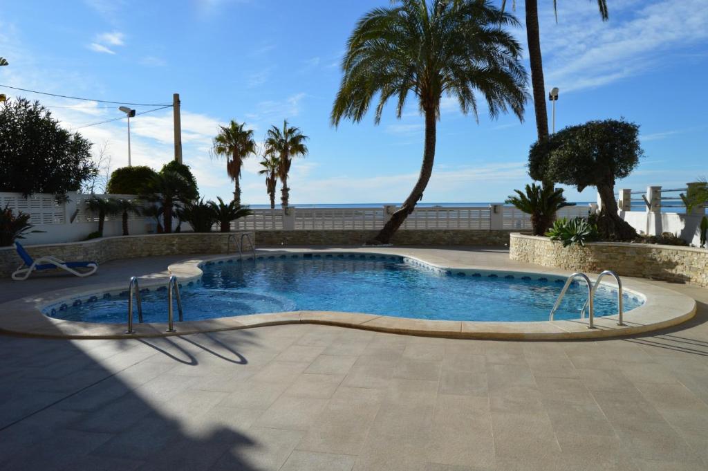 einen Pool mit Palmen und dem Meer in der Unterkunft Porto Azul 2 in Calpe