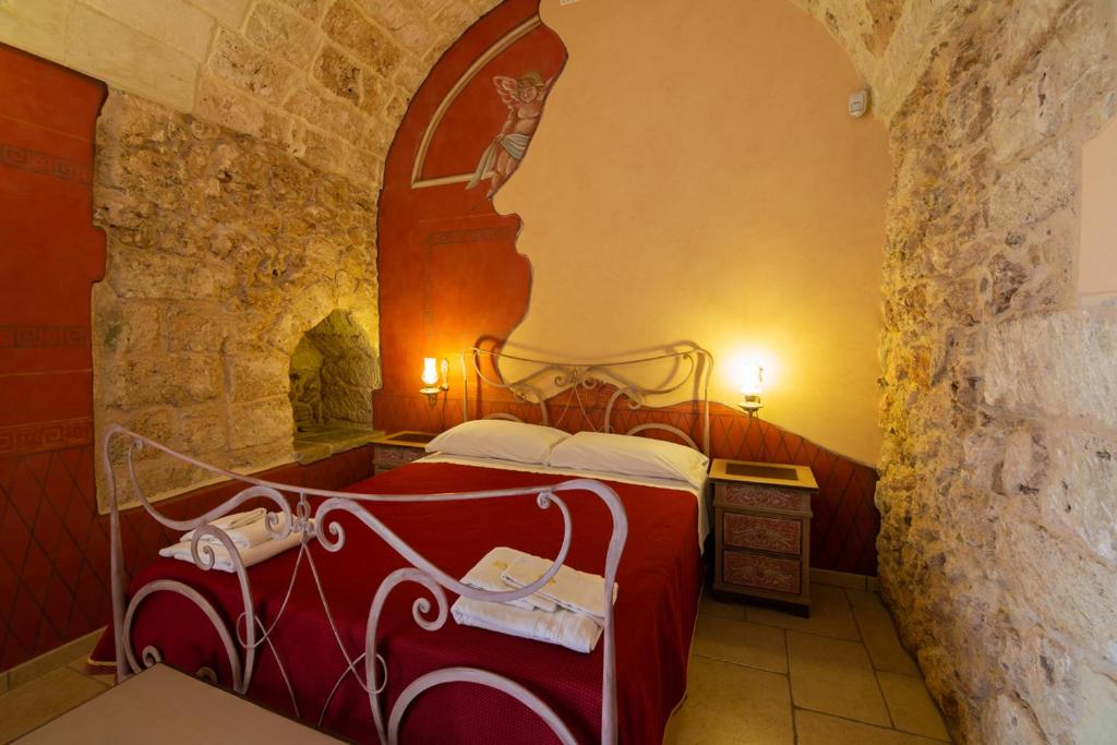 a bedroom with a red bed in a stone wall at Tenuta Masseria del Gallo in Calimera