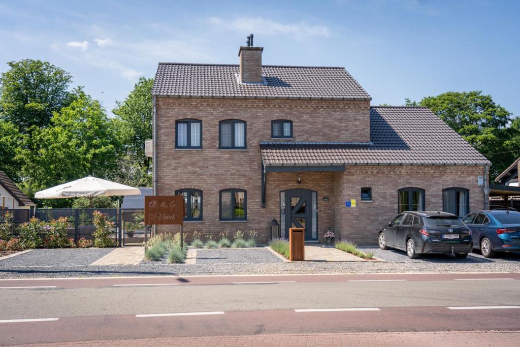 uma casa de tijolos com carros estacionados em frente em Bed & Breakfast 't Vèèrke em Dilsen-Stokkem