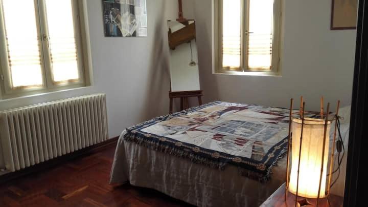 a bedroom with a bed with a lamp and two windows at accogliente appartamento a Parma in Case Nuove