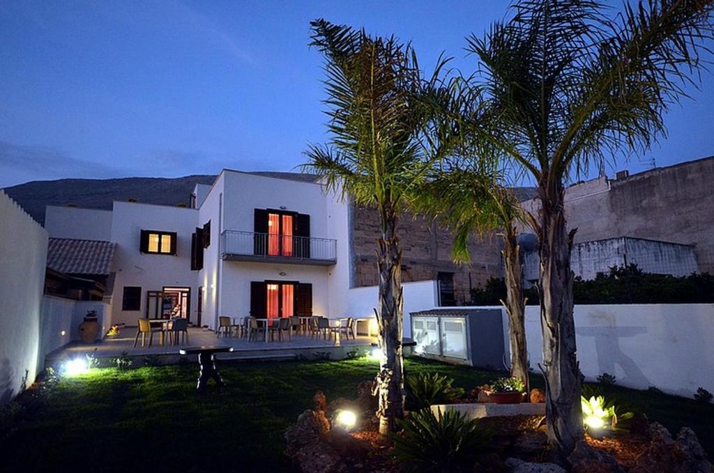 a large white house with palm trees and lights at Rotte e Sentieri B&B in Castelluzzo