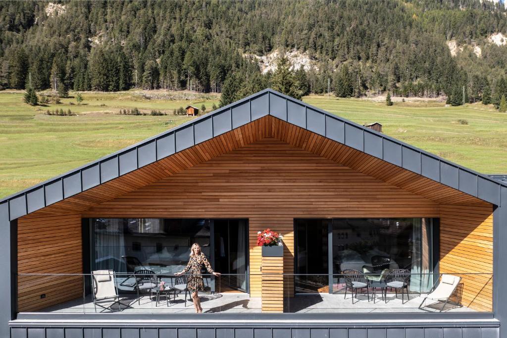 a woman walking in front of a house at Ladinia Dolomites View - Adults Only in Pozza di Fassa