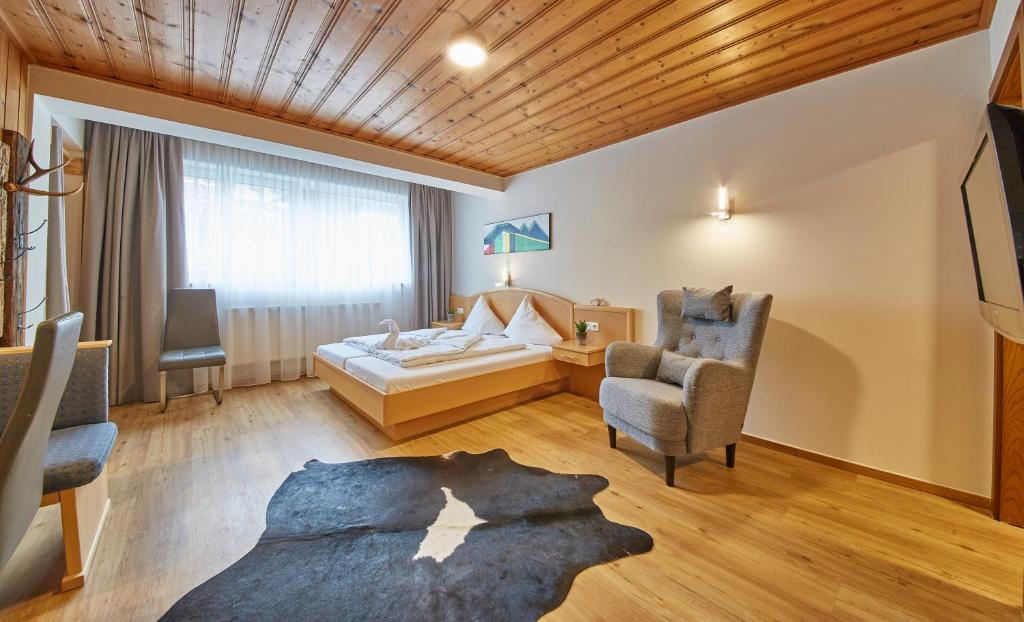 a hotel room with a bed and two chairs at Appartement Slope & Smile in Saalbach-Hinterglemm