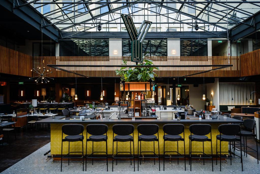 a restaurant with a large bar with yellow chairs at Yalo Urban Boutique Hotel Gent in Ghent