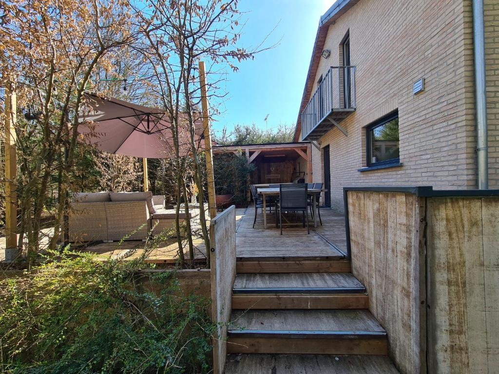 eine Holzterrasse mit einem Tisch und Stühlen auf einem Haus in der Unterkunft Entre l'eau in Durbuy