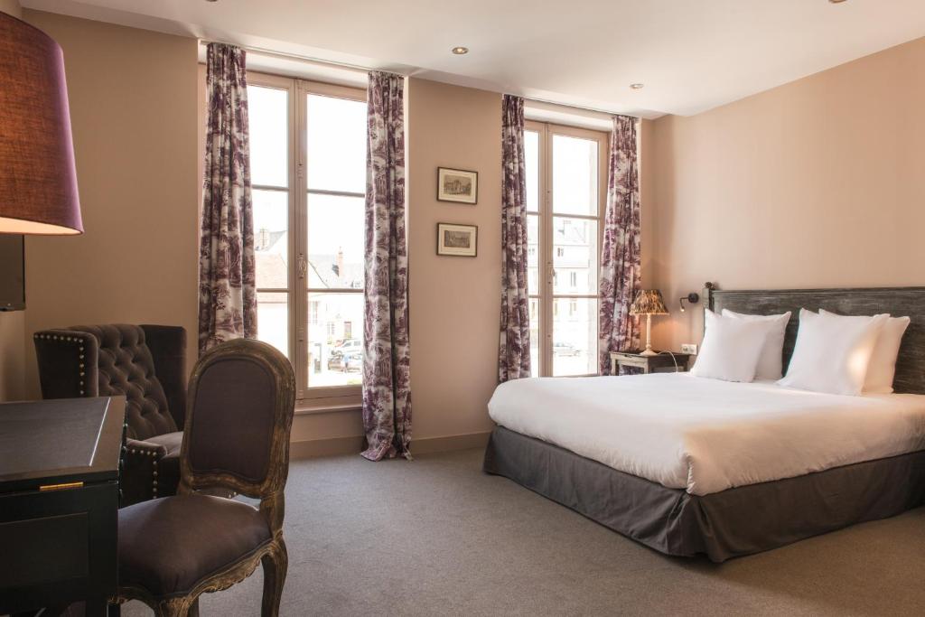 een hotelkamer met een bed, een bureau en een raam bij L'écu de Bretagne in Beaugency