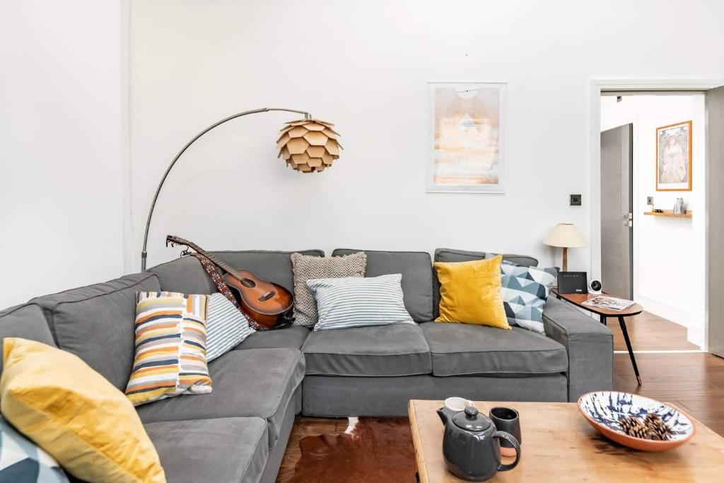 a living room with a gray couch with colorful pillows at Loft Apartment in Historic Building in Quiet Central Setting in Bristol