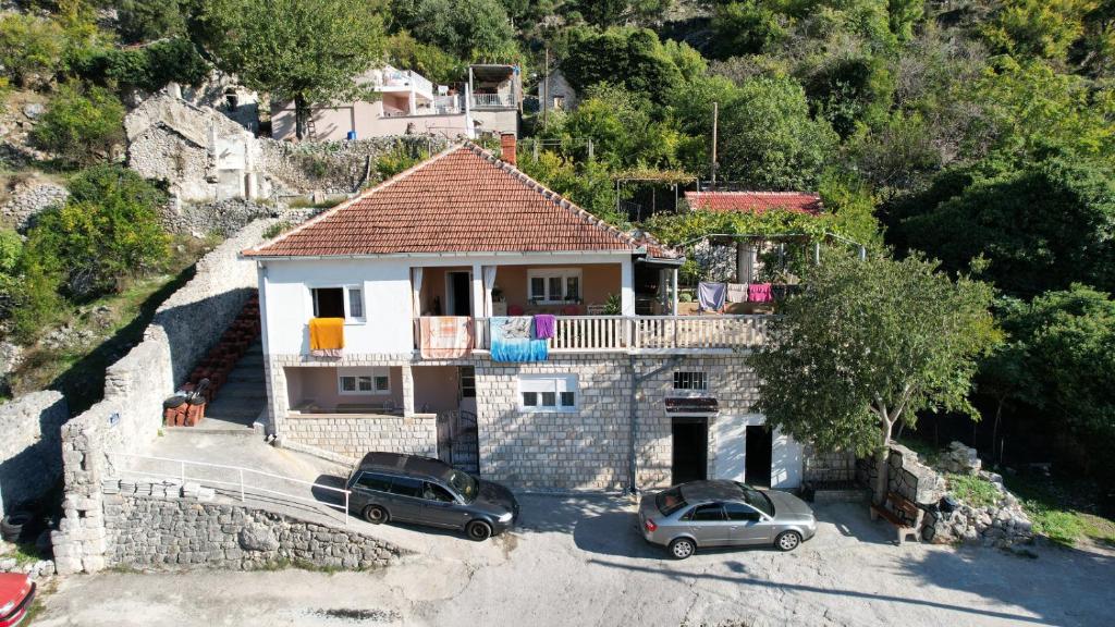una casa con dos coches estacionados frente a ella en Janina Hiša en Stolac