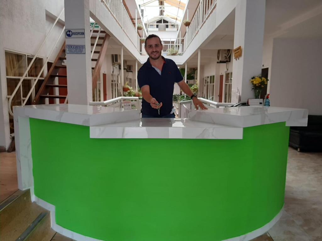 Ein Mann steht vor einer grünen und weißen Theke. in der Unterkunft Hotel Tame Real in Tame