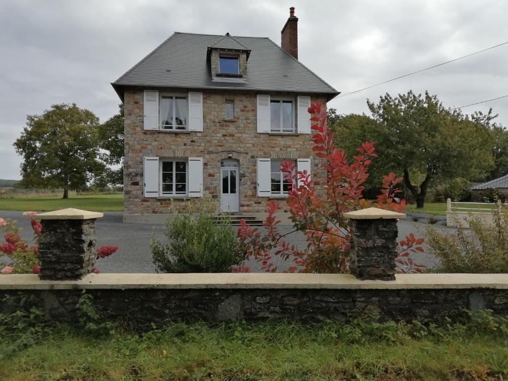 an old house with a stone wall in front of it at Le Lutice in Aunay-sur-Odon