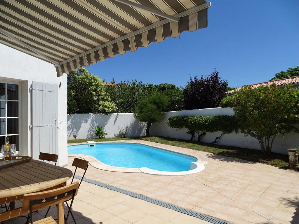 a swimming pool with a table and a patio at TETHYS VILLA AVEC PISCINE ET PROCHE DE LA MER in Sainte-Marie-de-Ré