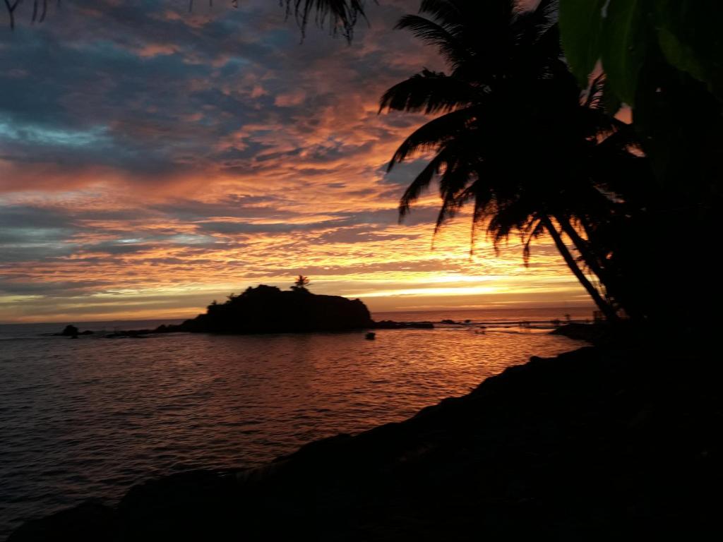 une personne debout sur un rocher dans l'océan au coucher du soleil dans l'établissement Seaside View, à Mirissa