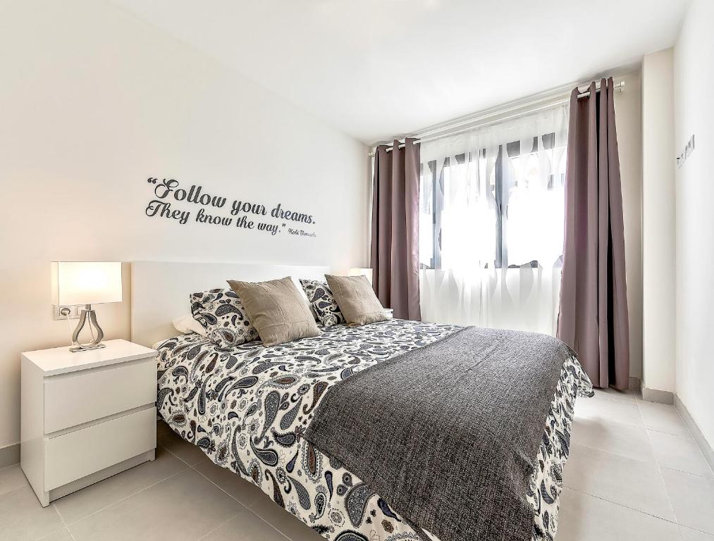 una camera da letto bianca con un letto e una finestra di Hortensia Suites Apartments ,Los Cristianos a Los Cristianos