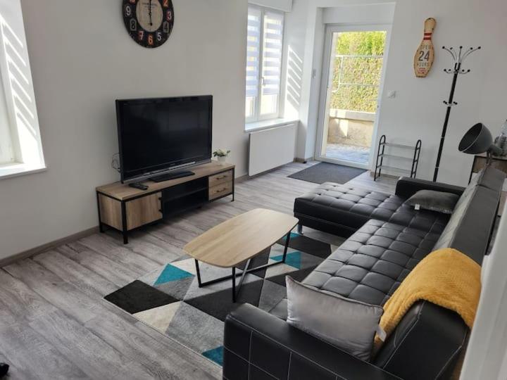 a living room with a couch and a flat screen tv at charmant appartement confort déco neuf , proche Epinal et Lac de Bouzey in Uxegney