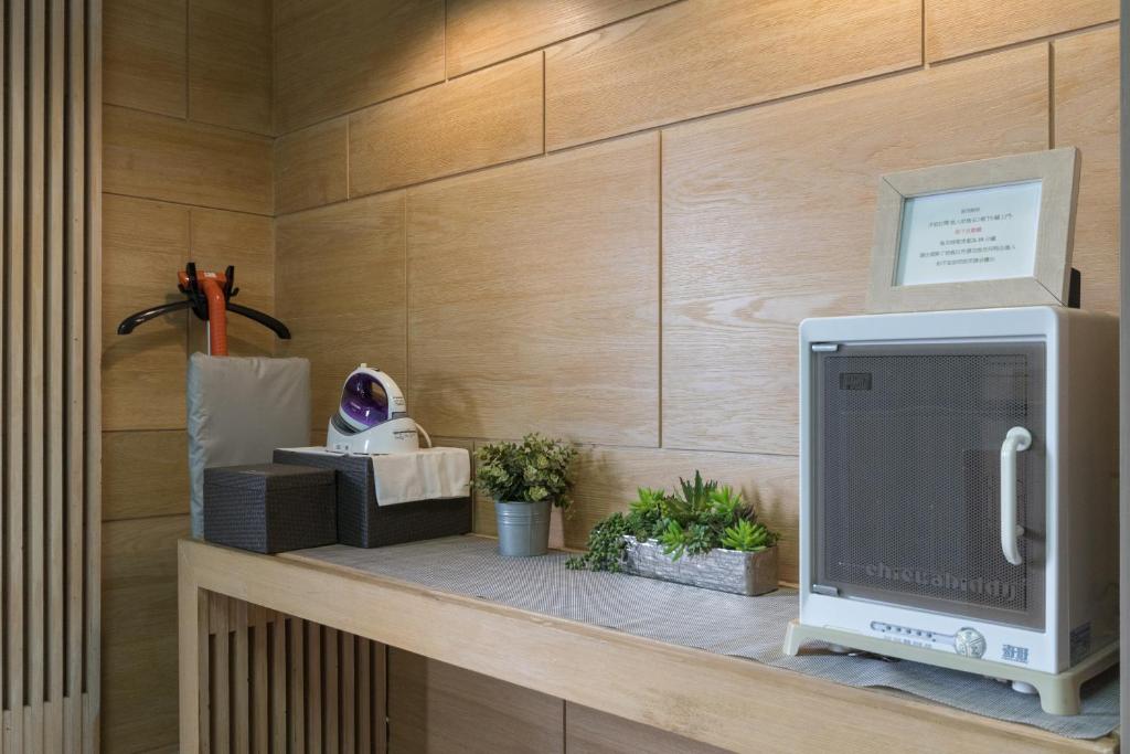 a computer monitor sitting on a shelf with plants at Just Enjoy Business Hotel in Tainan