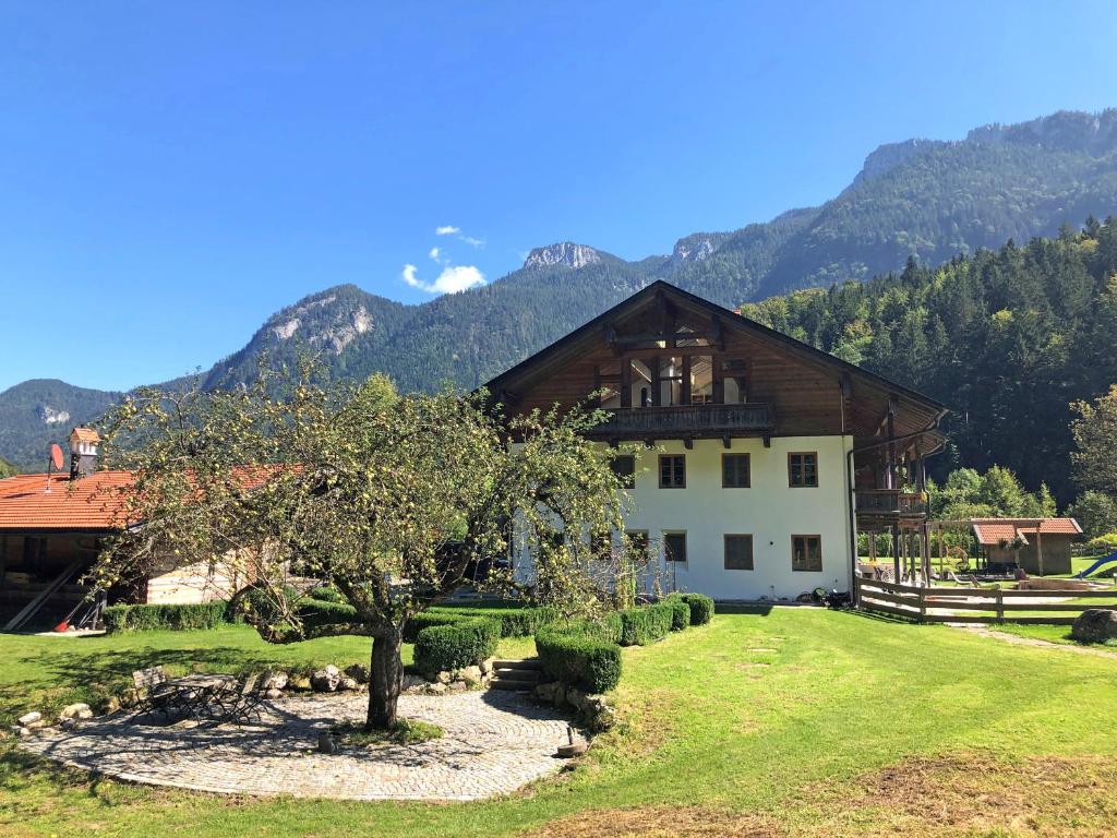une maison dans un champ avec un arbre et des montagnes dans l'établissement Cuka Designhome Aschau, à Aschau im Chiemgau