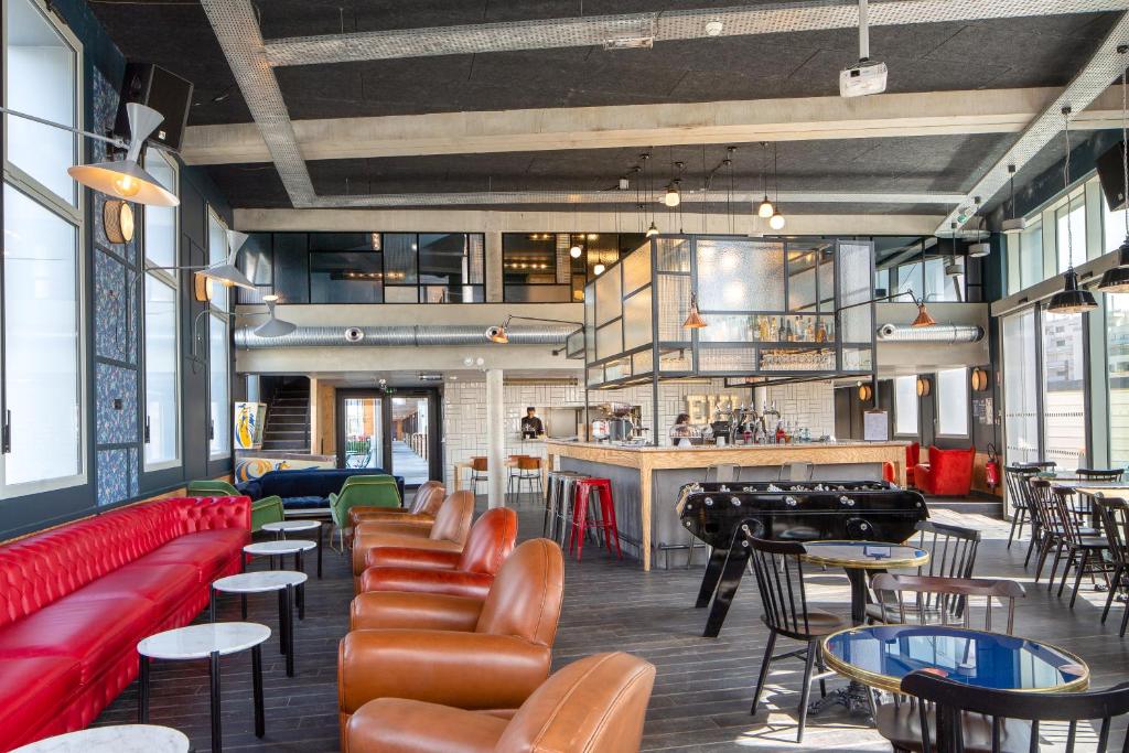 un restaurant avec des canapés et des tables rouges ainsi qu'un bar dans l'établissement Eklo Bordeaux Centre Bastide, à Bordeaux