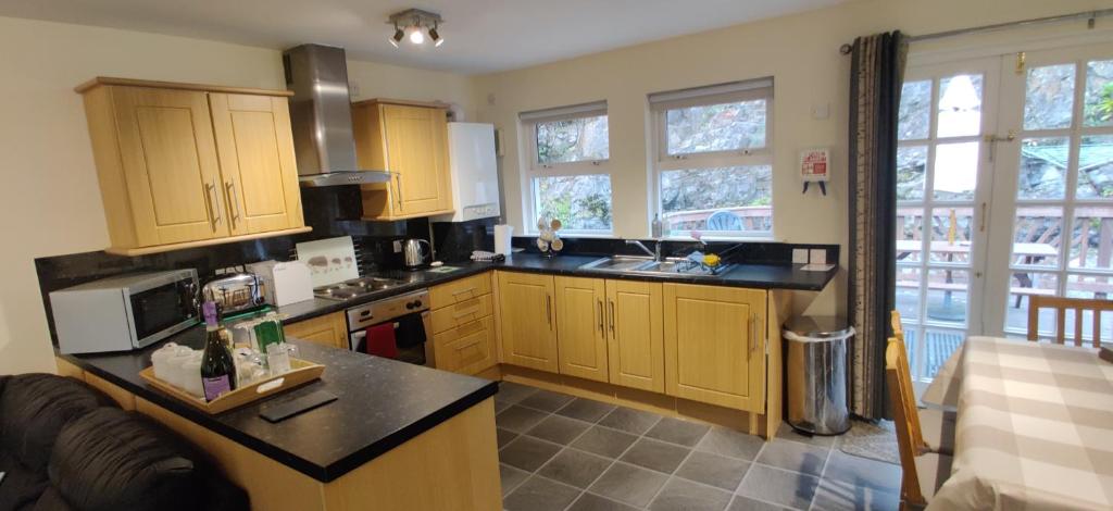 a kitchen with wooden cabinets and black counter tops at The Cobbler Cottage - Loch Lomond and Arrochar Alps in Arrochar