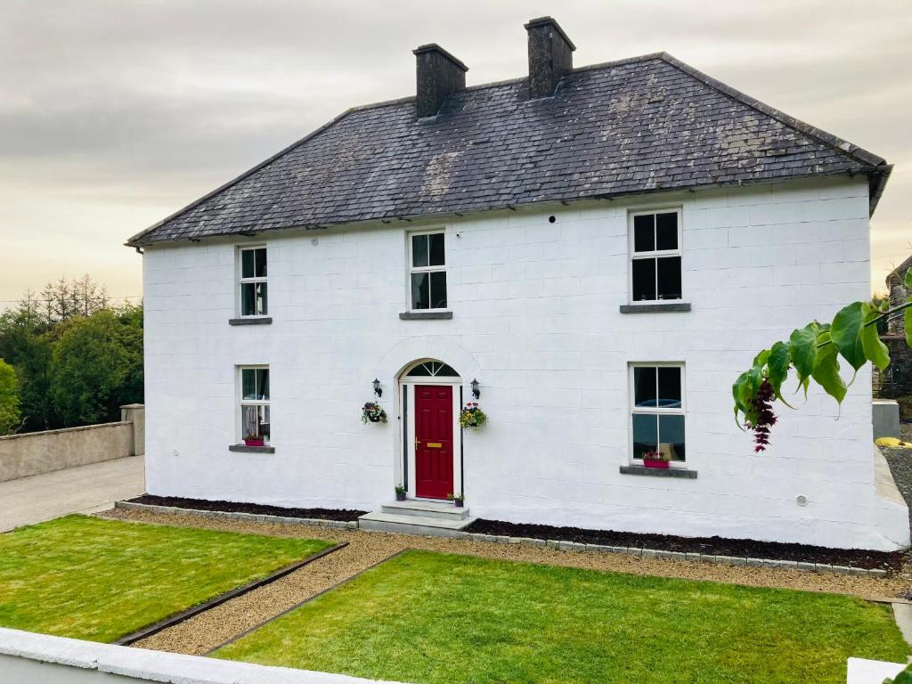 a white house with a red door at Entire Farmhouse in Tipperary in Nenagh