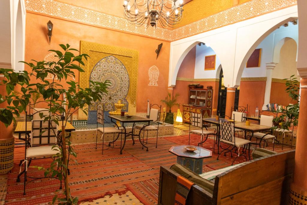ein Restaurant mit Tischen, Stühlen und einem Kronleuchter in der Unterkunft Riad Losra in Marrakesch