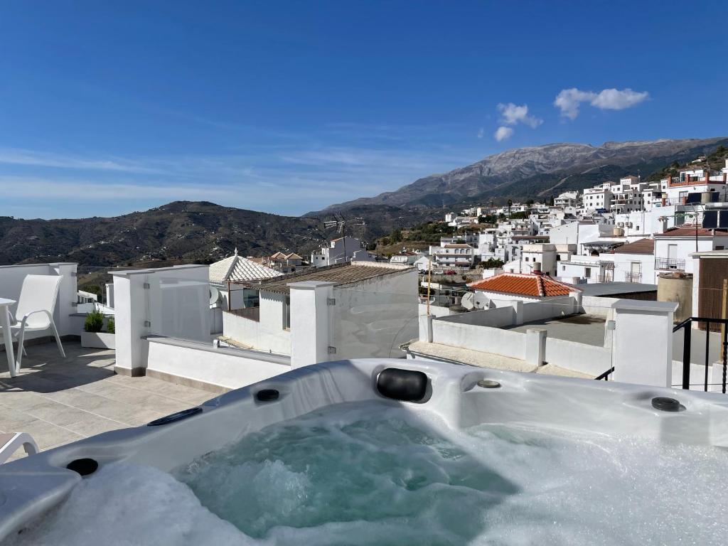 uma banheira de hidromassagem numa varanda com vista para a cidade em Casa Gato Azul em Cómpeta