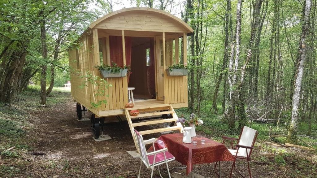 eine Holzhütte im Wald mit einem Tisch und Stühlen in der Unterkunft Lovely shepherds hut in chauminet in Sougères-en-Puisaye