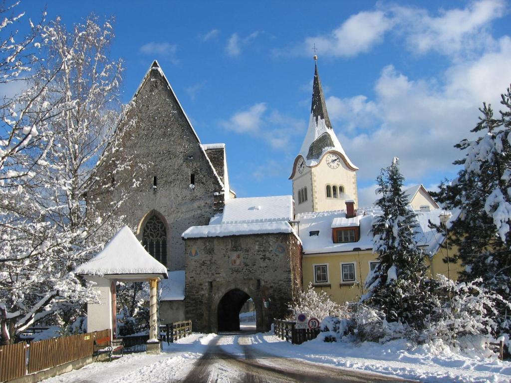 a church in the snow with snow covered trees at Pension Geissler-Reicher in Oberwölz Stadt