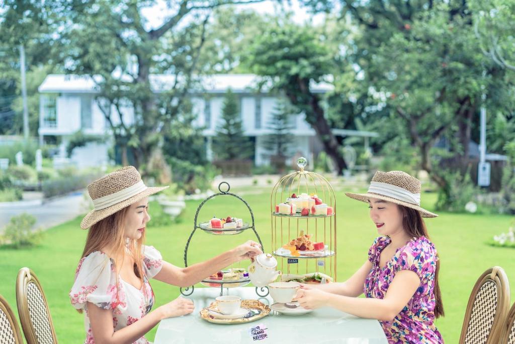 two women sitting at a table with a cake in a bird cage at Tree Tara hotel in Lampang