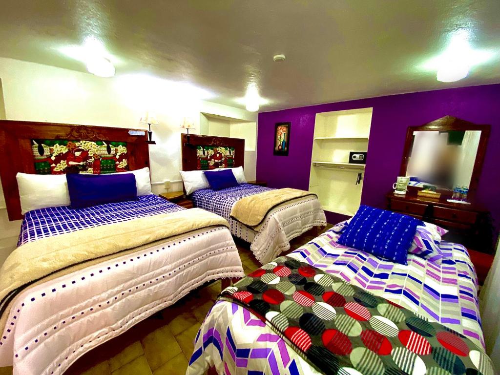 two beds in a room with purple walls at Hotel Magdalena Colonial in Guanajuato