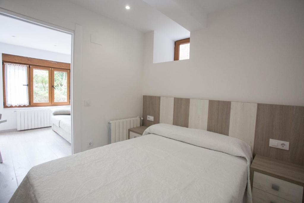 a white bedroom with a bed and a mirror at La Riega in Potes