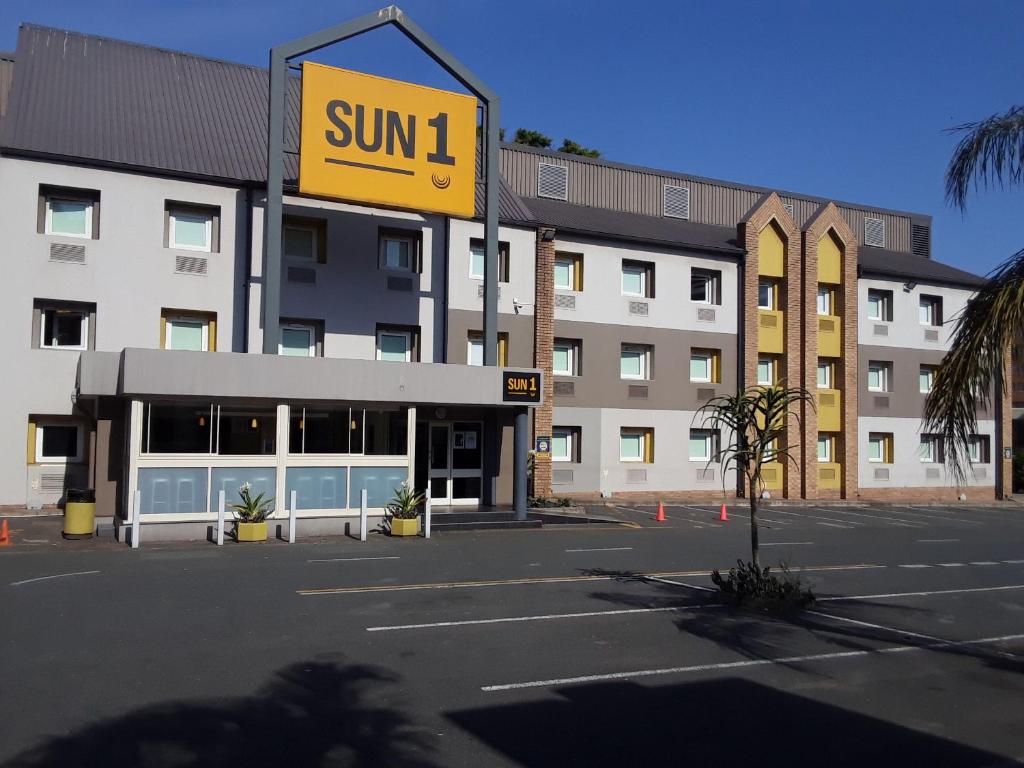 un edificio con una señal solar frente a un aparcamiento en SUN1 Durban, en Durban
