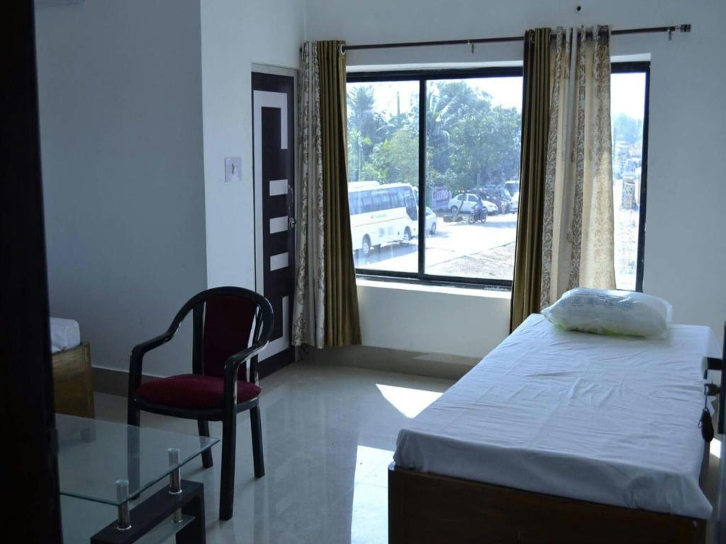 a bedroom with a bed and a chair and a window at PAGODAINN in Konārka