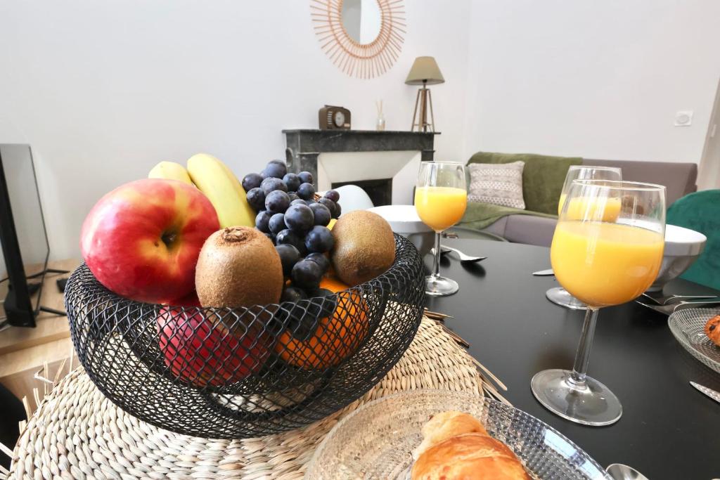 a bowl of fruit on a table with glasses of orange juice at Napoléon Gare 3 T2 RDC ByLocly in Pontivy