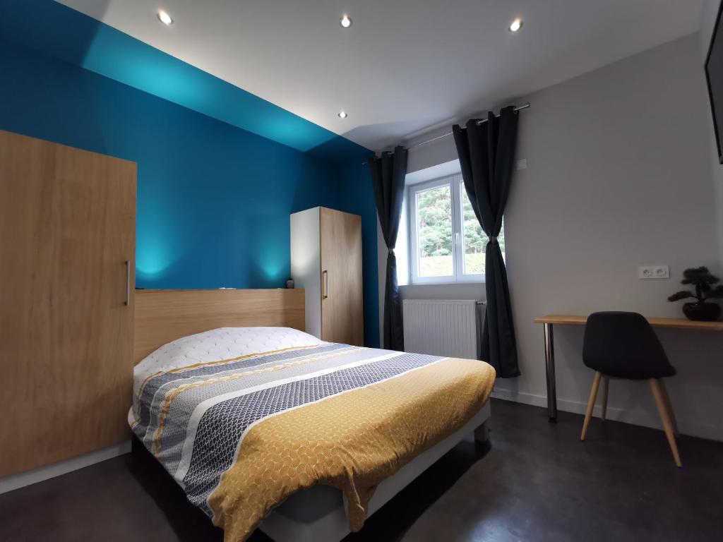 een slaapkamer met een bed en een blauwe muur bij La bonne adresse in Sainte-Sigolène