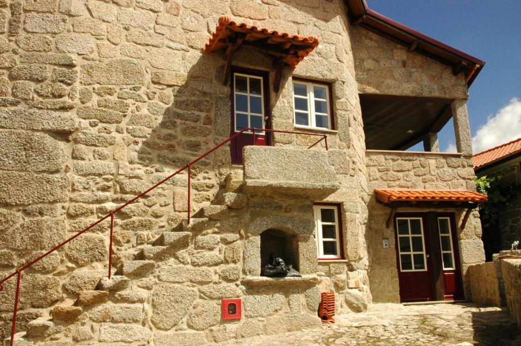 um cão sentado à porta de um edifício de pedra em Casa de Campo Monte Abades em Terras de Bouro