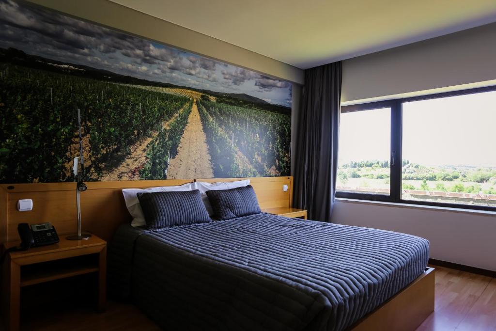 a bedroom with a bed with a painting on the wall at Burguezia do Leitão in Casal Comba