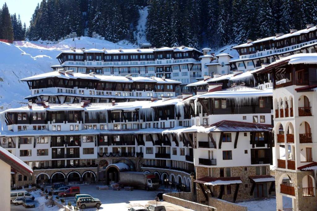 un groupe de bâtiments avec de la neige sur leurs toits dans l'établissement Grand Monastery Private Apartment, à Pamporovo