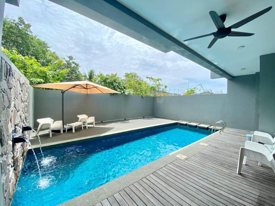 - une piscine avec une terrasse et un parasol dans l'établissement LeGrace Villa Langkawi Private Pool, à Pantai Cenang