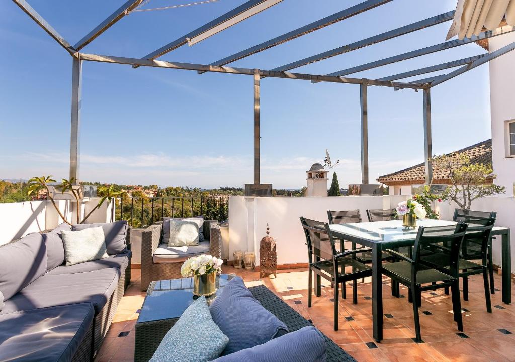 マルベーリャにある4 bedroom Holiday Penthouse near Puerto Banus, in Nueva Andaluciaのパティオ(ソファ、テーブル、椅子付)