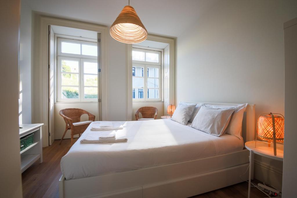 a bedroom with a large white bed and two windows at Solar Studio Fontainhas in Porto