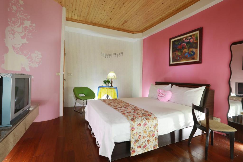 a pink room with a bed and a tv at Xiang Heng House in Luodong